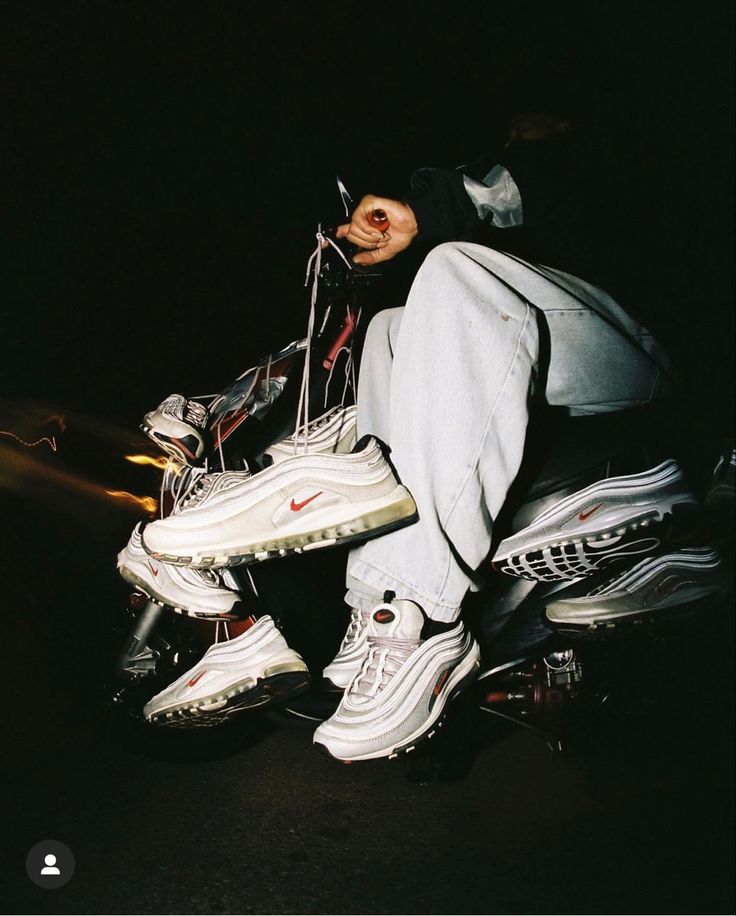 a man sitting on top of a motorcycle in the dark with his foot propped up