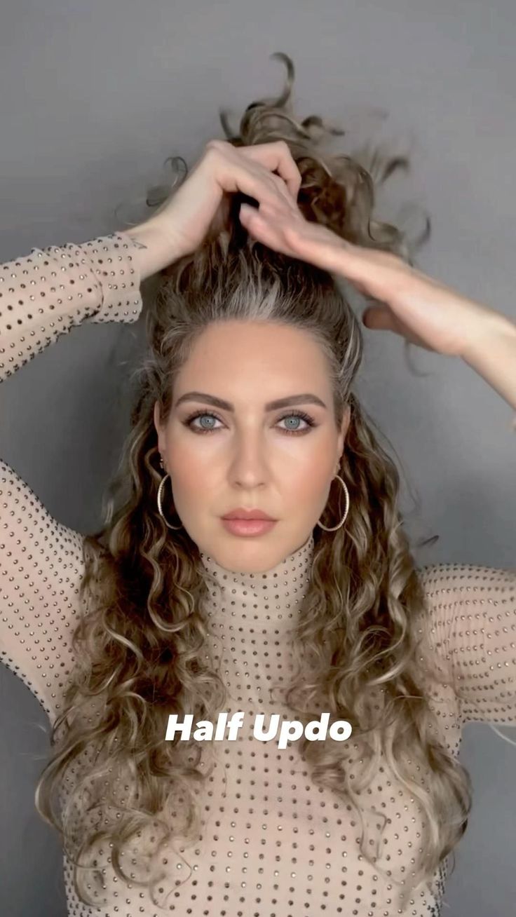 a woman with curly hair is holding her hands up to her head and the words half updo above her head