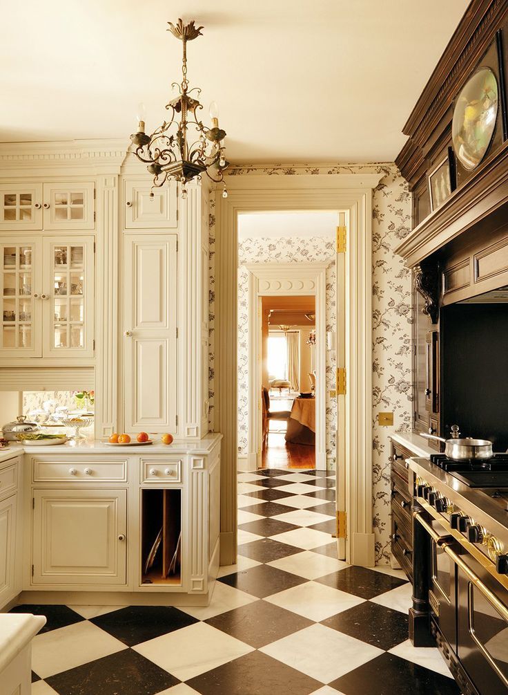 a kitchen with black and white checkered flooring, chandelier and cabinets