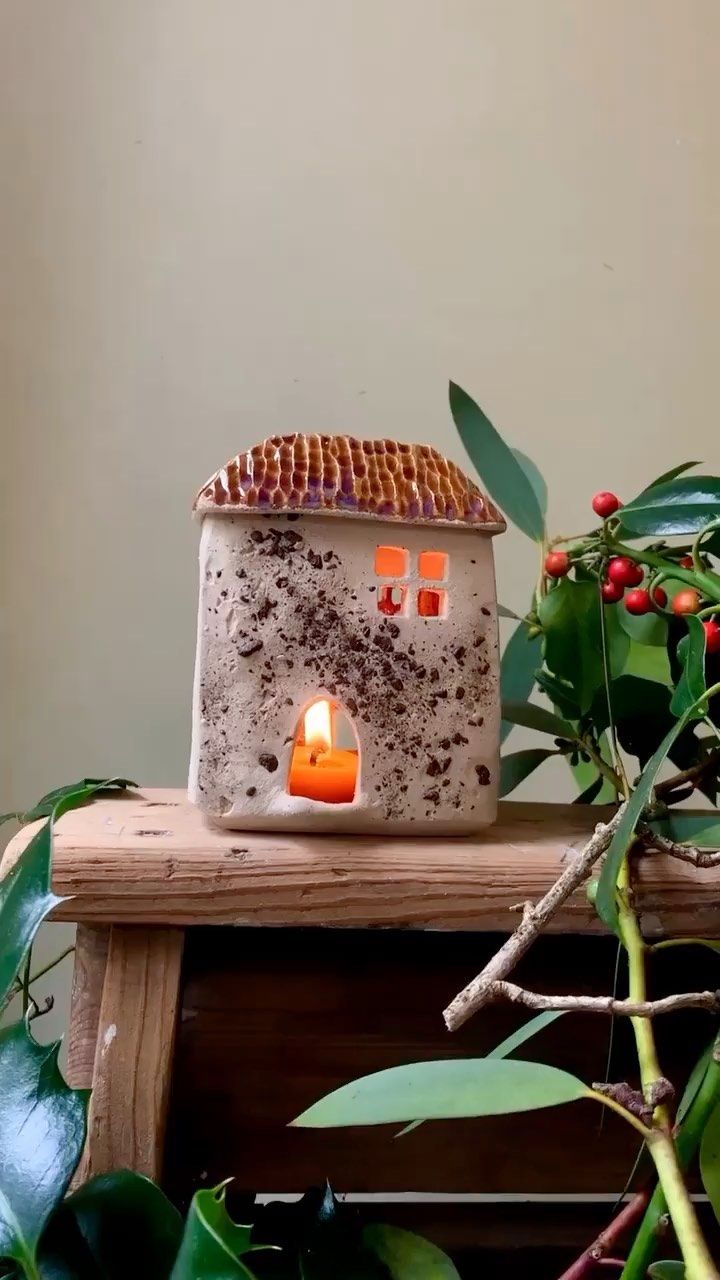 a small house candle holder sitting on top of a wooden table