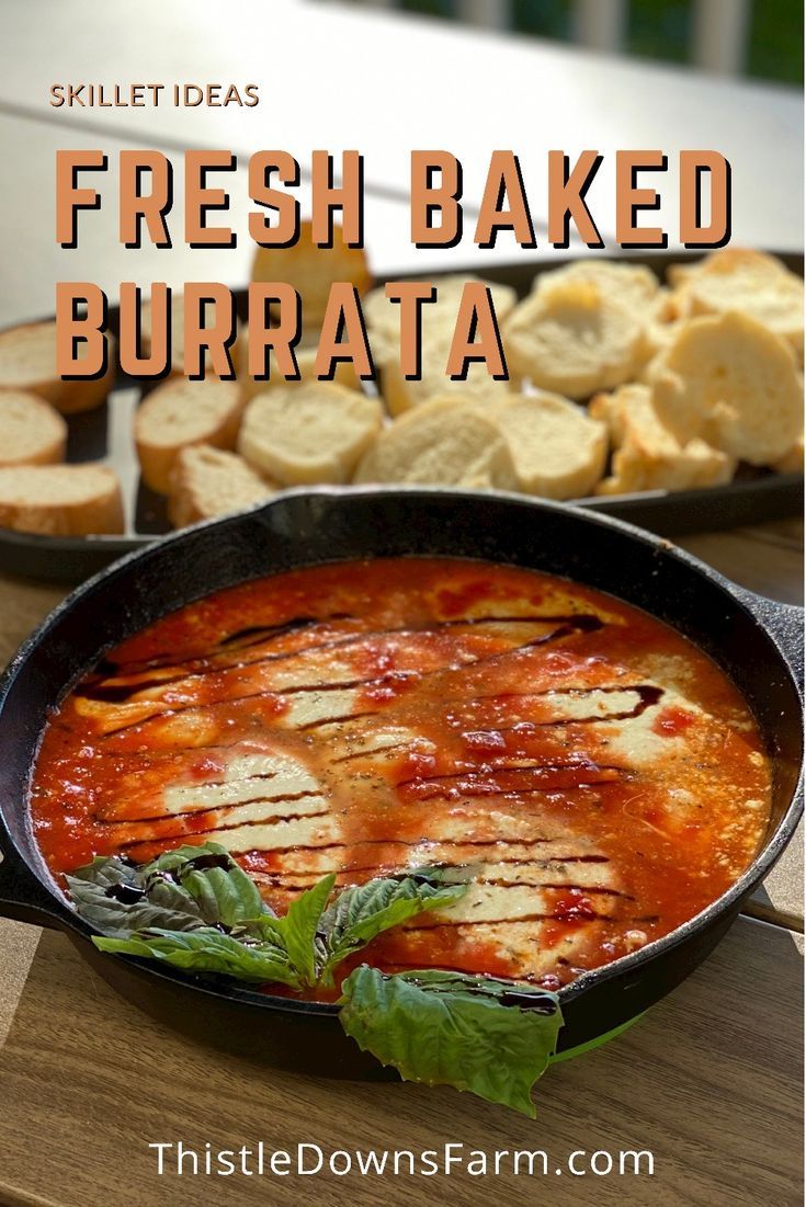 fresh baked burrataa in a skillet with basil leaves on the side and bread slices