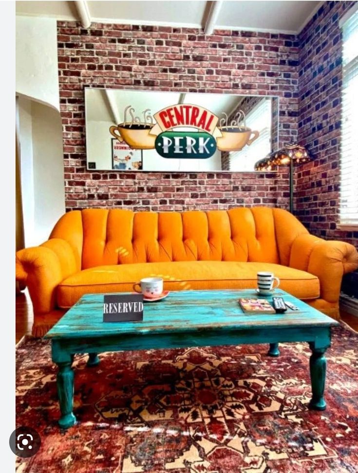 an orange couch sitting in front of a brick wall