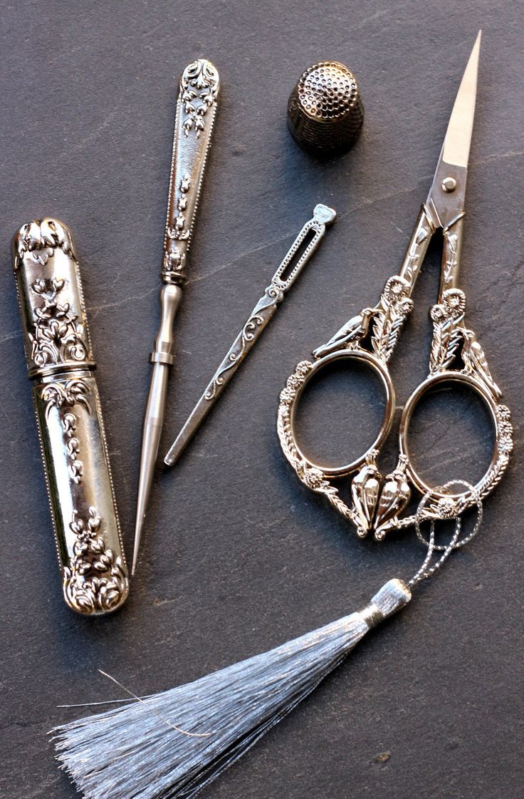 an assortment of antique scissors and other items on a table with a ball in the background