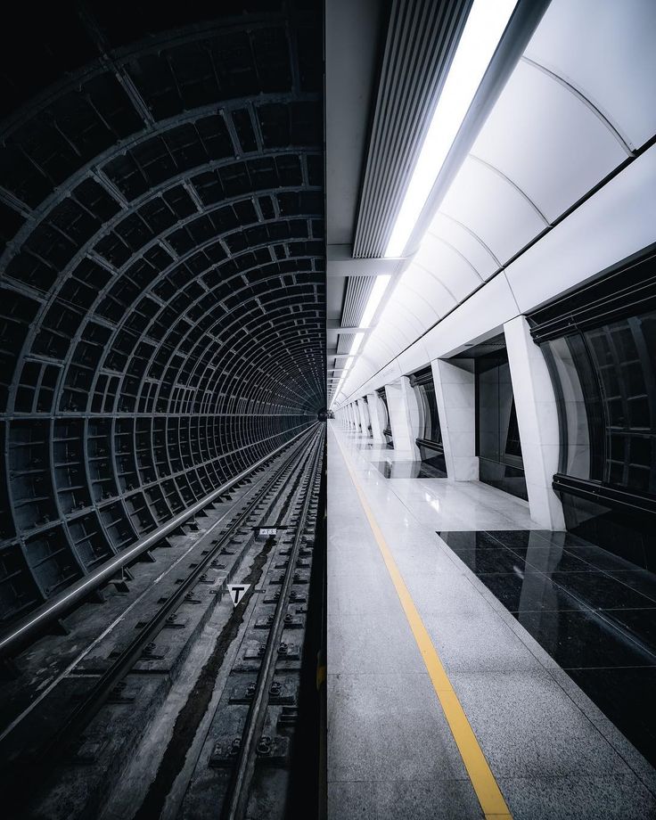 an empty subway station with no people on the platform and only one person in the tunnel