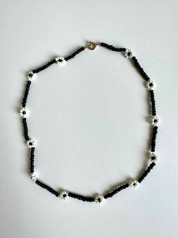 Elevate your style with this stunning black and white flower beaded choker necklace. Handcrafted with care, this unique piece blends elegance with a touch of edginess, making it perfect for any occasion. The monochrome color scheme ensures versatility, complementing both casual outfits and evening ensembles effortlessly. Whether you're treating yourself or searching for a thoughtful gift, this choker promises to add a dash of floral charm to your jewelry collection. Embrace timeless beauty with our black and white flower choker today! Details: ☆ Handmade item! ☆ Length: 15 in ☆ Perfect for: Everyday wear, special occasions, gifts Please make sure your address is correct before purchasing! For any questions don't hesitate to contact me :) Black Flower-shaped Jewelry With Colorful Beads, Black Flower Choker As A Gift, Black Flower Pendant Necklace With Charm, Black Flower Choker For Gifts, Black Flower Charm Jewelry, Handmade Black Flower Necklace, Adjustable Black Flower Pendant Necklace, Black Adjustable Flower Pendant Necklace, Trendy Black Flower-shaped Jewelry