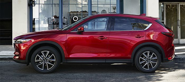 a red mazda cx - 5 parked in front of a building