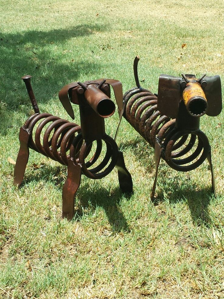 two metal dogs made to look like they are standing in the grass with their tails curled up