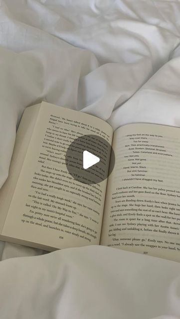 an open book sitting on top of a bed next to white sheets and pillow covers