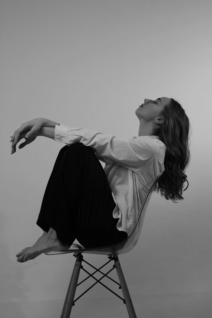 a woman sitting on top of a chair with her arms outstretched in the air while looking up