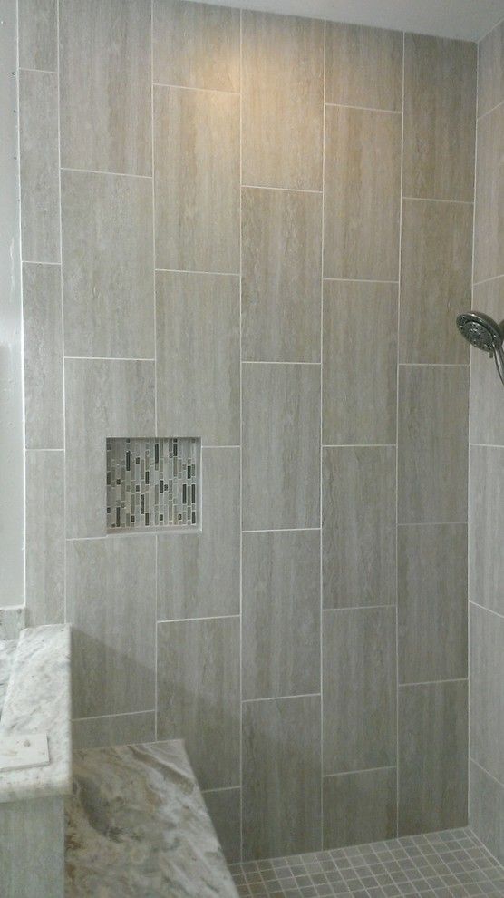 a walk in shower sitting next to a white sink under a faucet mounted on a wall