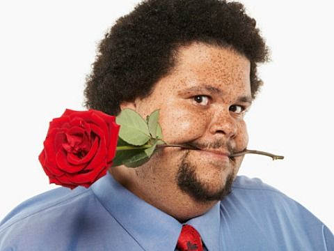 a man with a rose in his mouth is holding a stick to his nose and looking at the camera