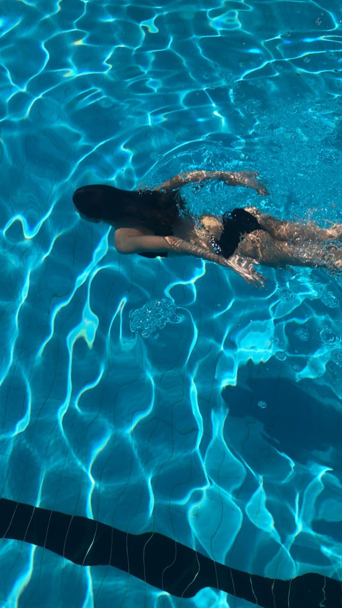 a woman swimming in a pool with her back to the camera