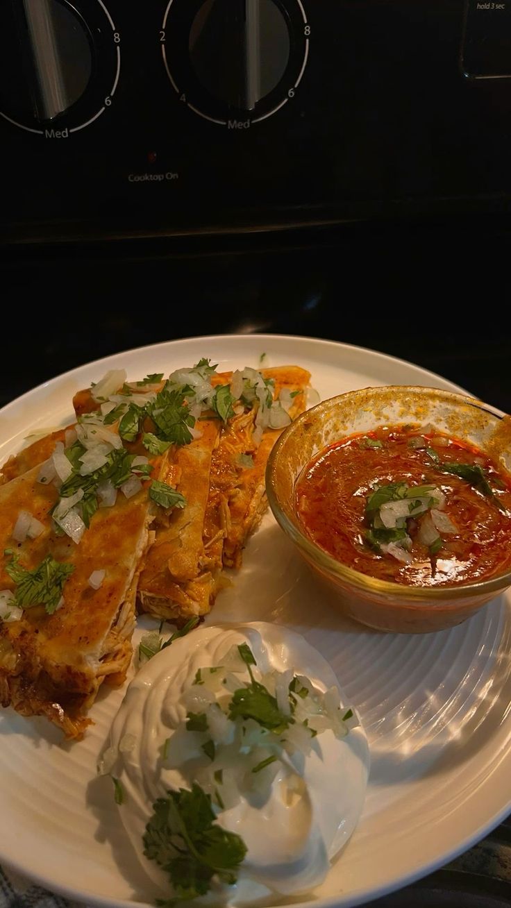 a white plate topped with food next to a bowl of salsa and tortilla