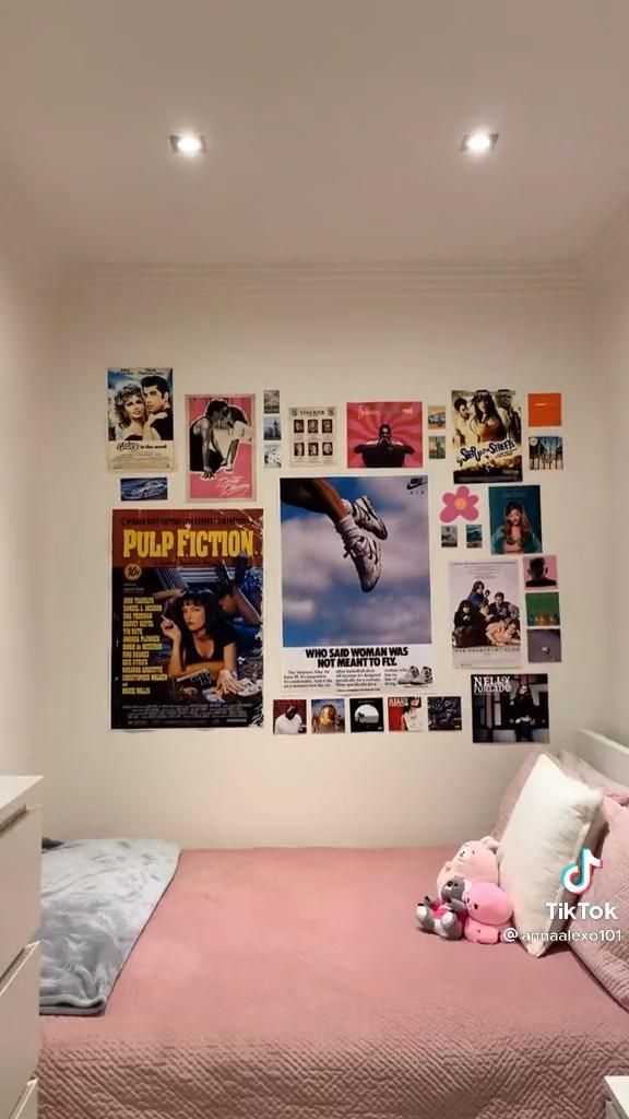 a bedroom with pink bedding and posters on the wall