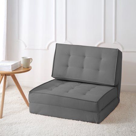 a gray couch sitting on top of a white rug next to a table with a cup