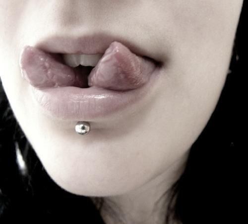 a close up of a woman's nose with a piercing on her lip and tongue ring