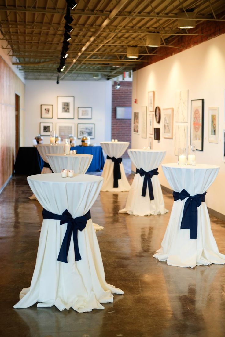 the tables are decorated with white linens and blue sashes for centerpieces