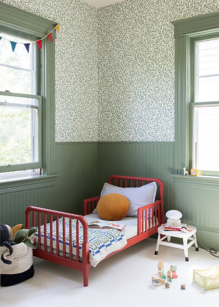 a small child's bed in the corner of a room with green painted walls