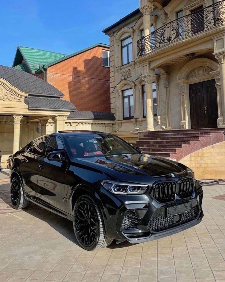 a black bmw x5 parked in front of a large building with steps leading up to it