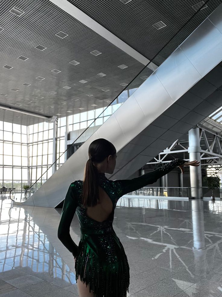 a woman in a green dress is pointing at something on the floor with her hand