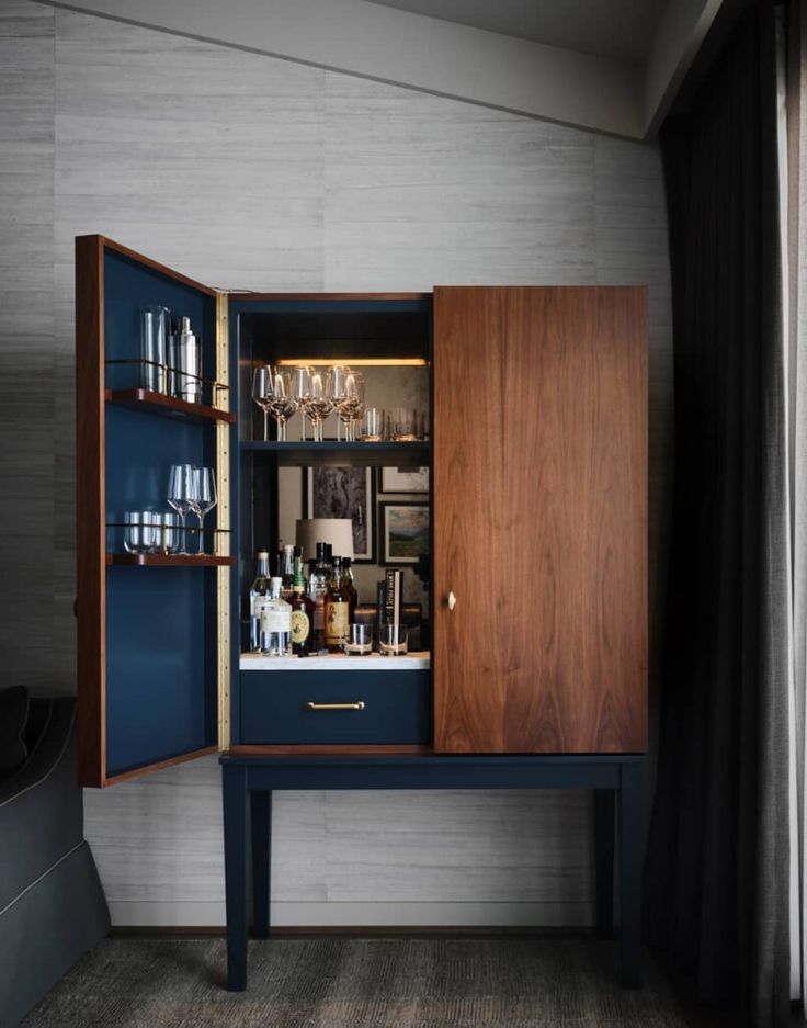 an open cabinet in the corner of a room with wine glasses and liquor bottles on it