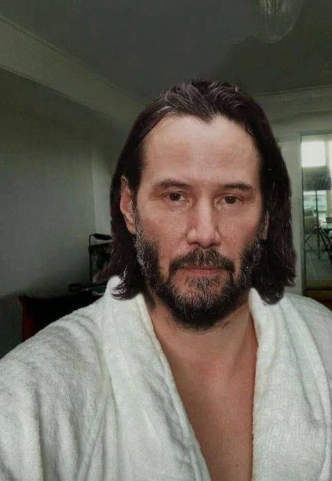 a man with long hair and beard wearing a white bathrobe looking at the camera