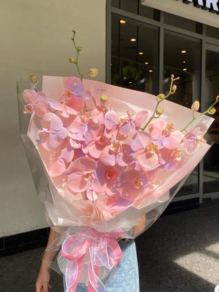 a woman holding a bouquet of pink flowers