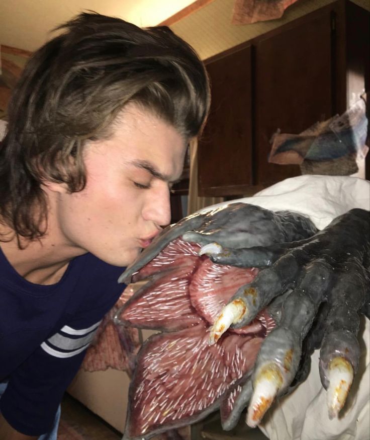 a young man kissing an animal on the nose with his hands wrapped around it's body