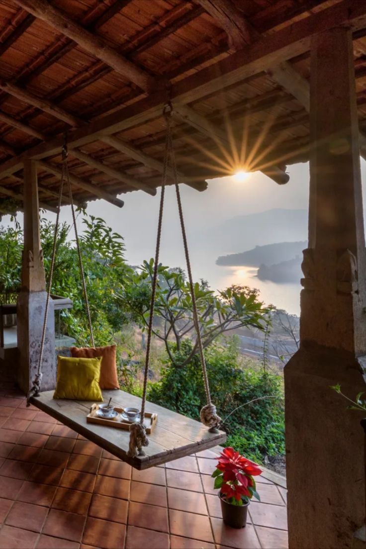 a porch with a swing, potted plant and water view in the back ground