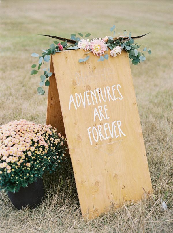 there is a sign that says adventures are forever next to some flowers in the grass