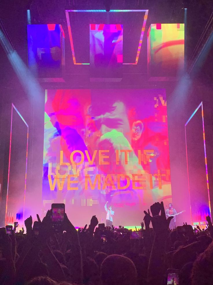 the stage is lit up with bright colored lights and people are standing in front of it