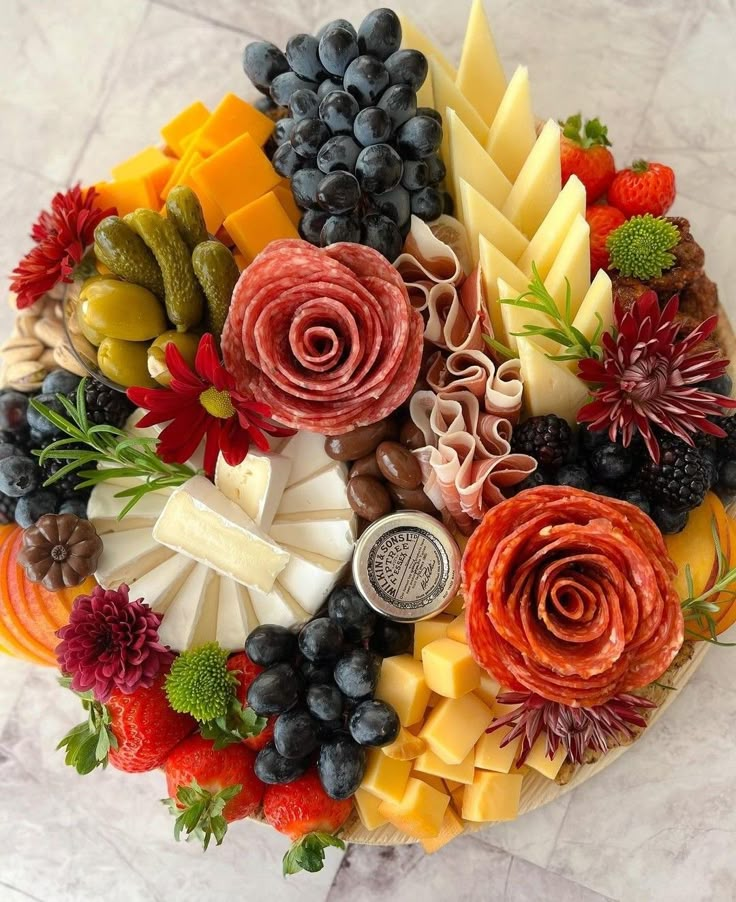 a platter filled with different types of cheeses and fruits on top of a marble table