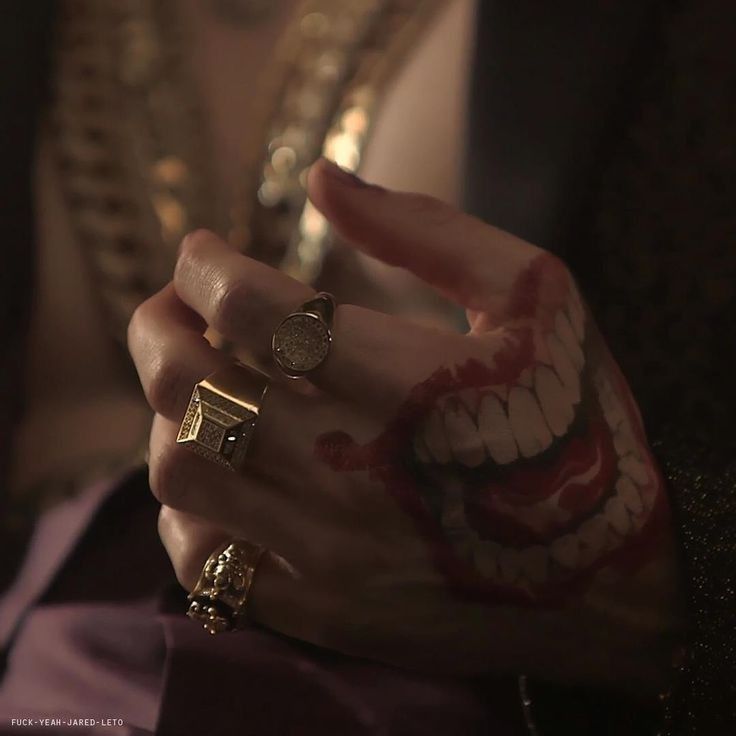 a close up of a person's hand with rings on their fingers and mouth