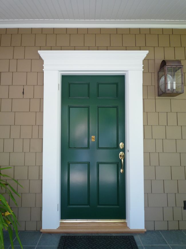 a green front door with white trim on a house