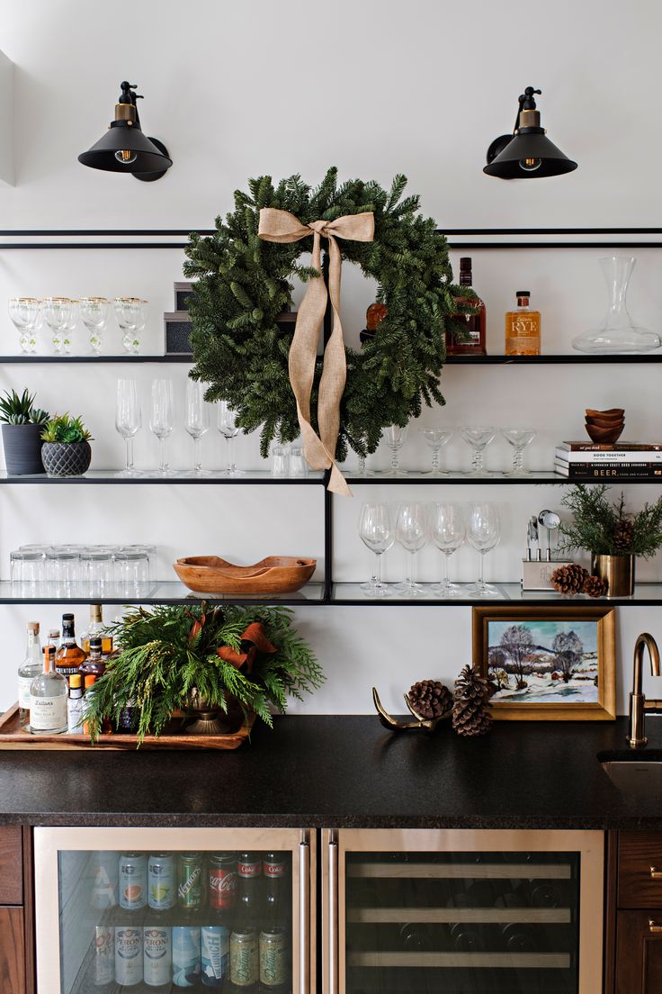 a christmas wreath is hanging on the wall above a wine cooler and other holiday decorations