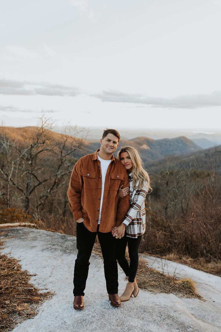 a man and woman standing on top of a mountain