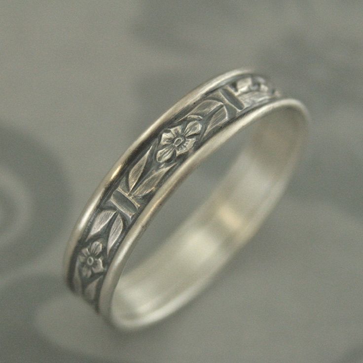 a silver ring with flowers and leaves on it