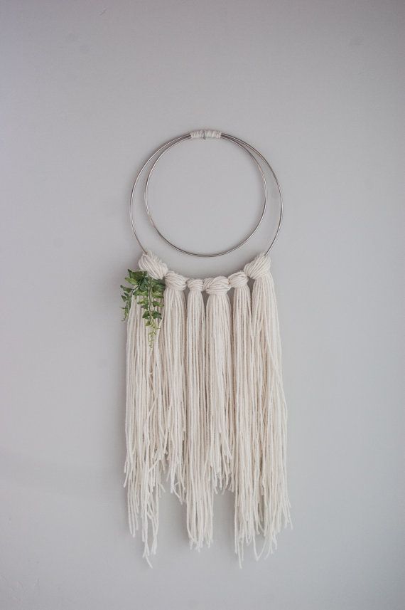 a white wall hanging on the side of a wall with two circular rings and flowers