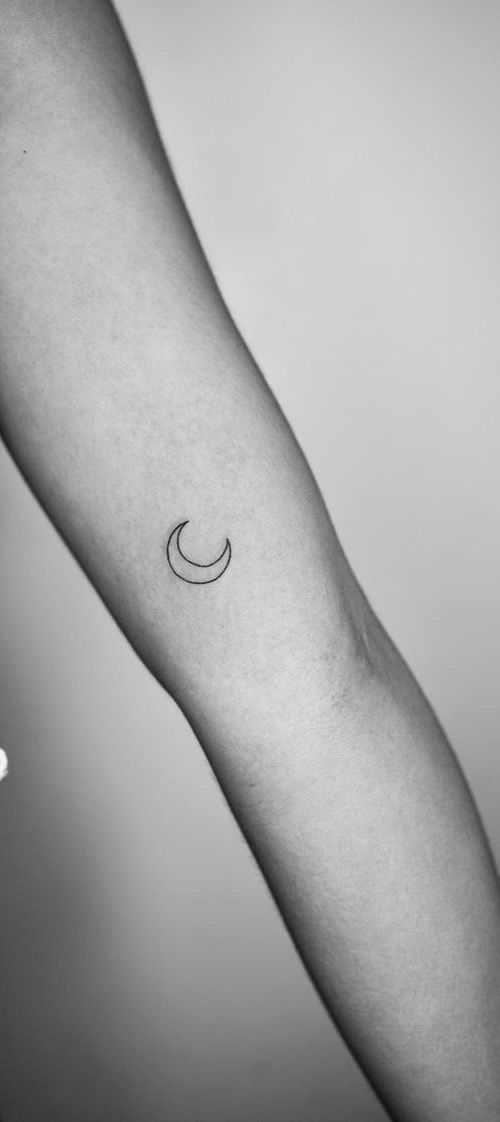 a person's arm with a small crescent tattoo on the left side of their arm