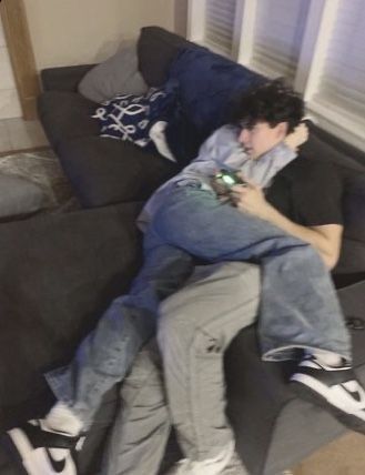 a man sitting on the back of a couch while holding onto another person's arm