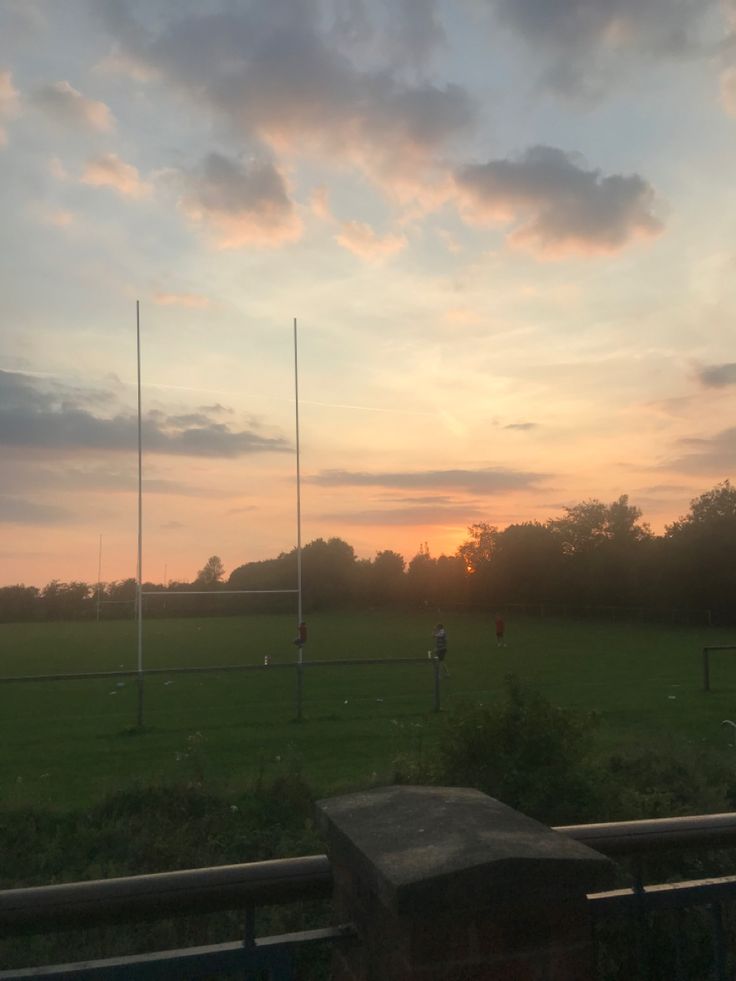 the sun is setting over a soccer field