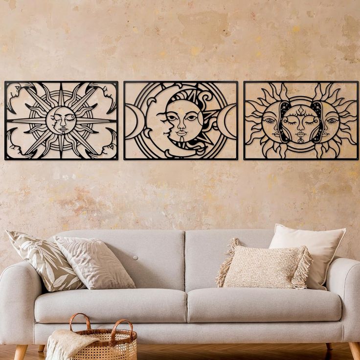 a living room with three sun and moon wall art on the walls, along with a gray couch