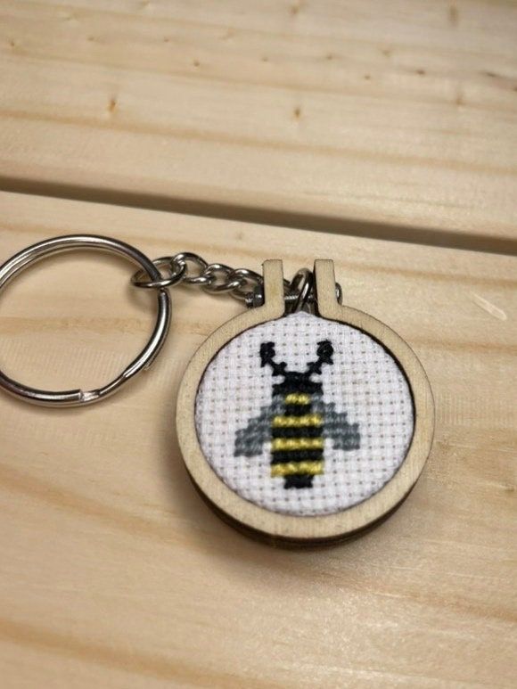 a cross stitch keychain with a bee on it