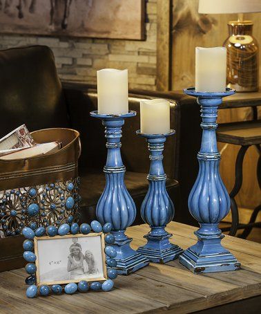 three blue candles sitting on top of a wooden table next to a framed photo and some beads