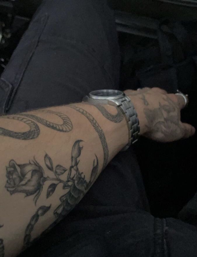 a man with tattoos on his arm sitting in a car