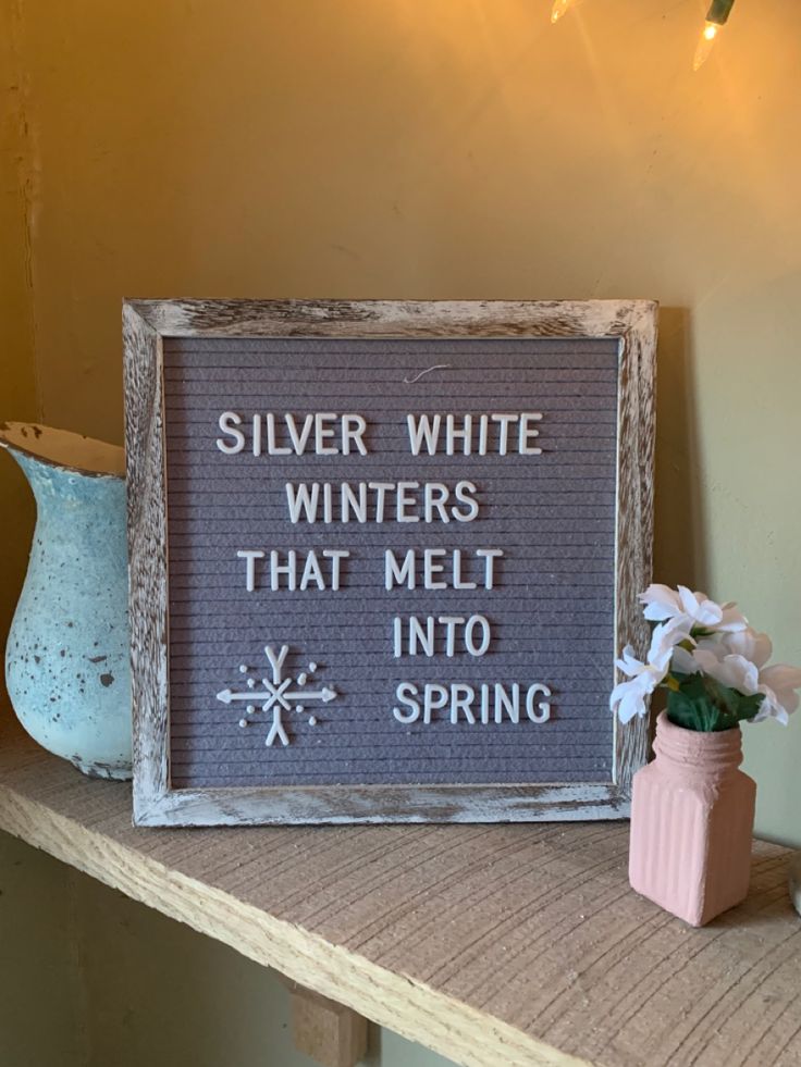 a sign that says silver white winters that melt into spring next to a vase with flowers