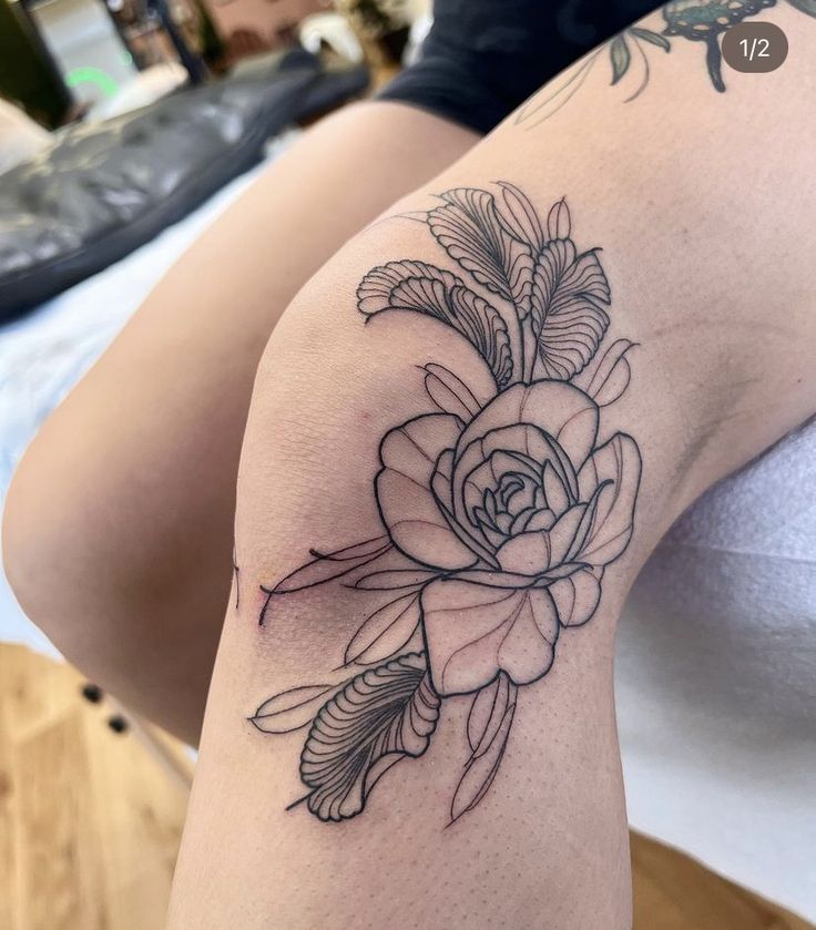 a woman's thigh with a rose tattoo on her arm and the bottom half of her leg