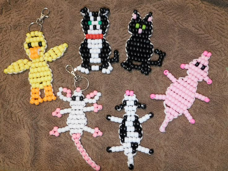 four beaded keychains are sitting on a towel, one has a cat and the other is a dog