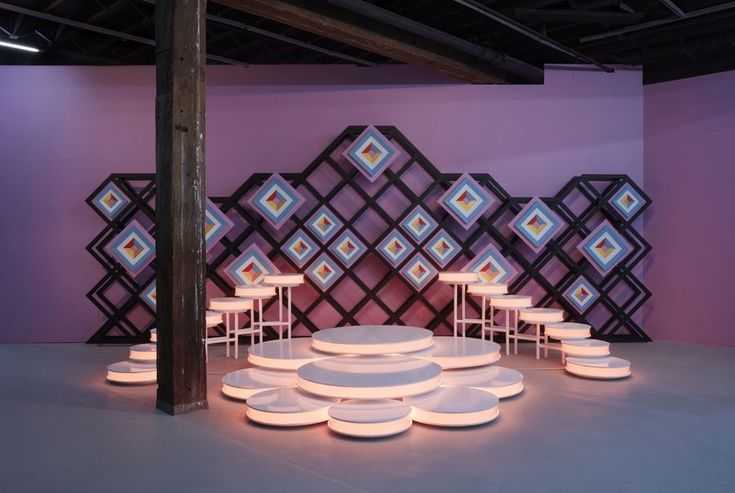 a room filled with white plates on top of a floor next to a wall covered in geometric designs