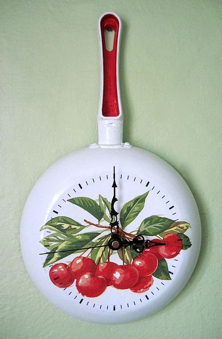 a white clock with cherries painted on it's face hanging from the wall